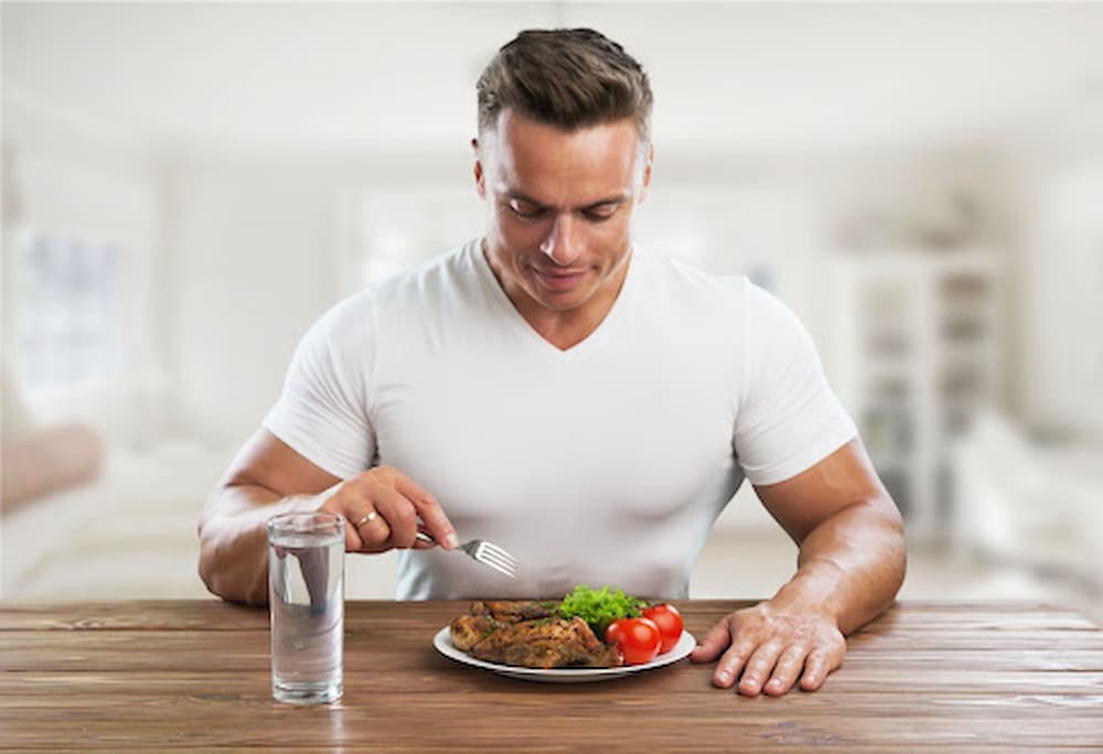 Man sitting at table with a glass of water and plate of healthy food