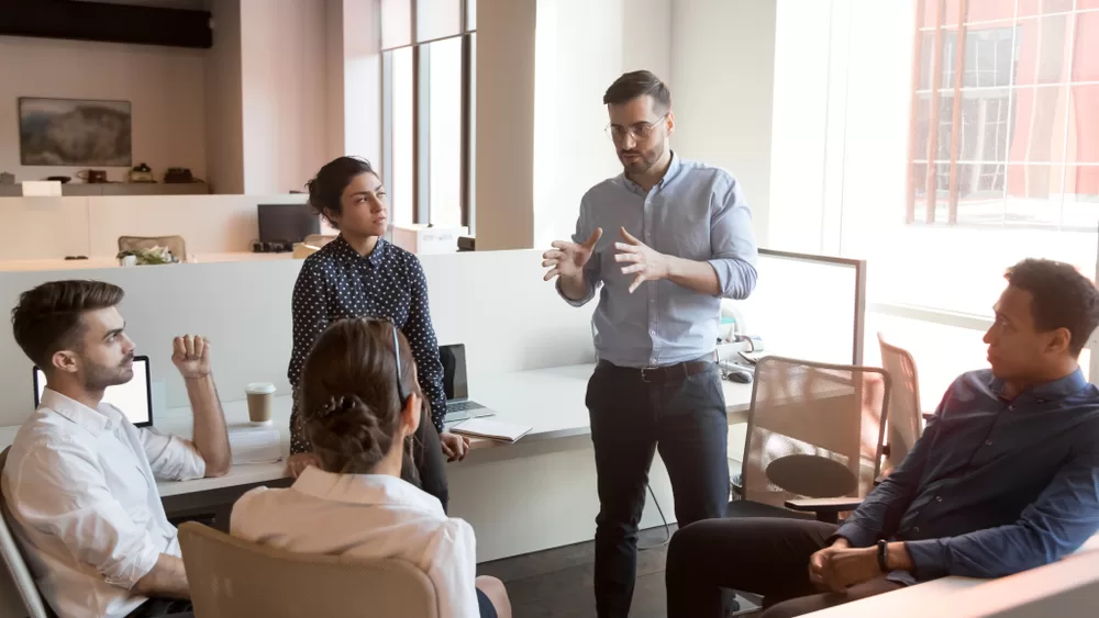 Man leading team meeting while coworkers listen