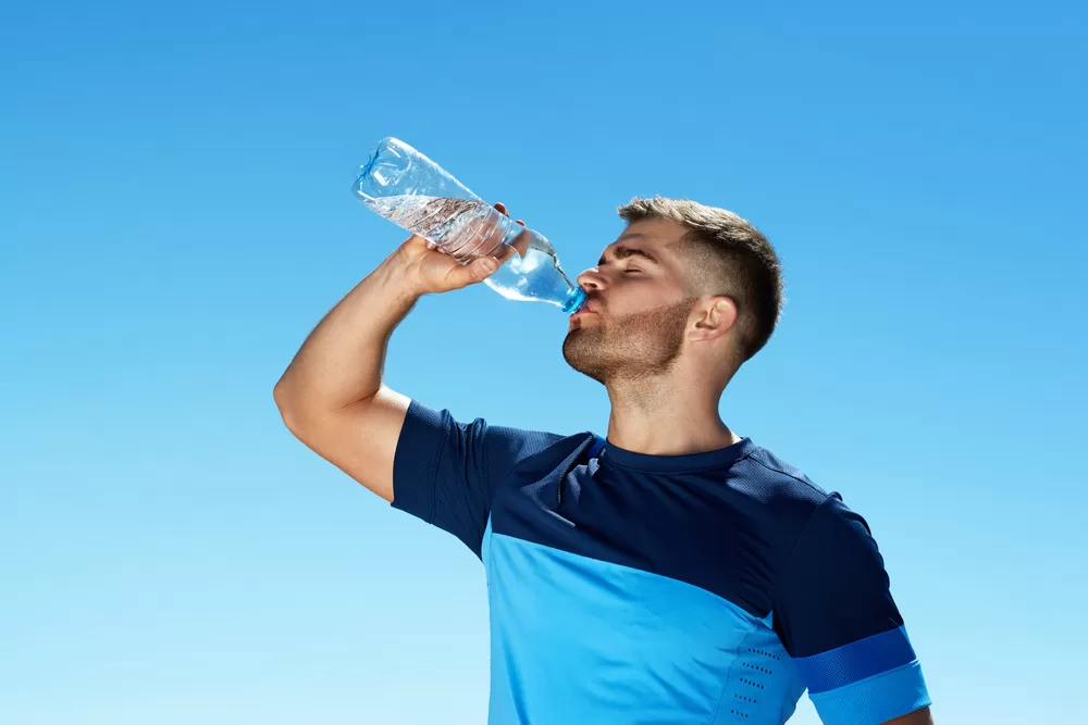 Man drinking water outside on sunny day
