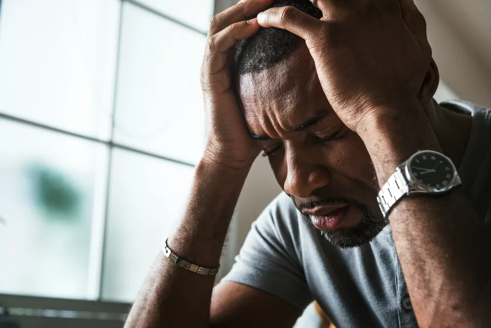 Stressed African American man holding his head in his hands