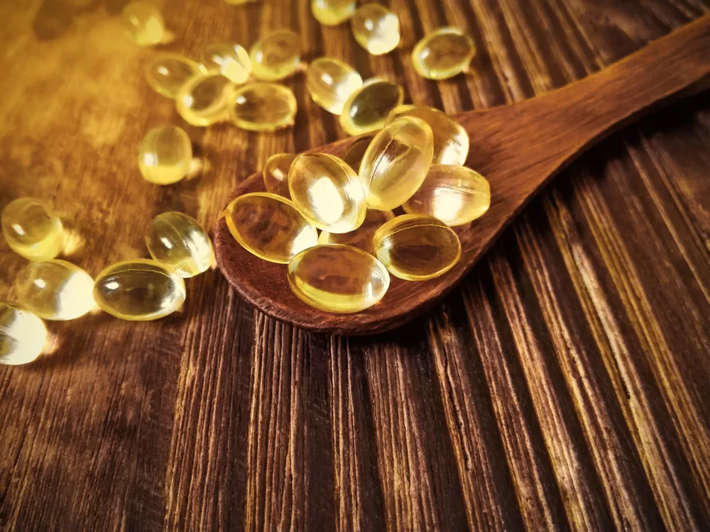 Vitamin capsules on wooden scoop on table