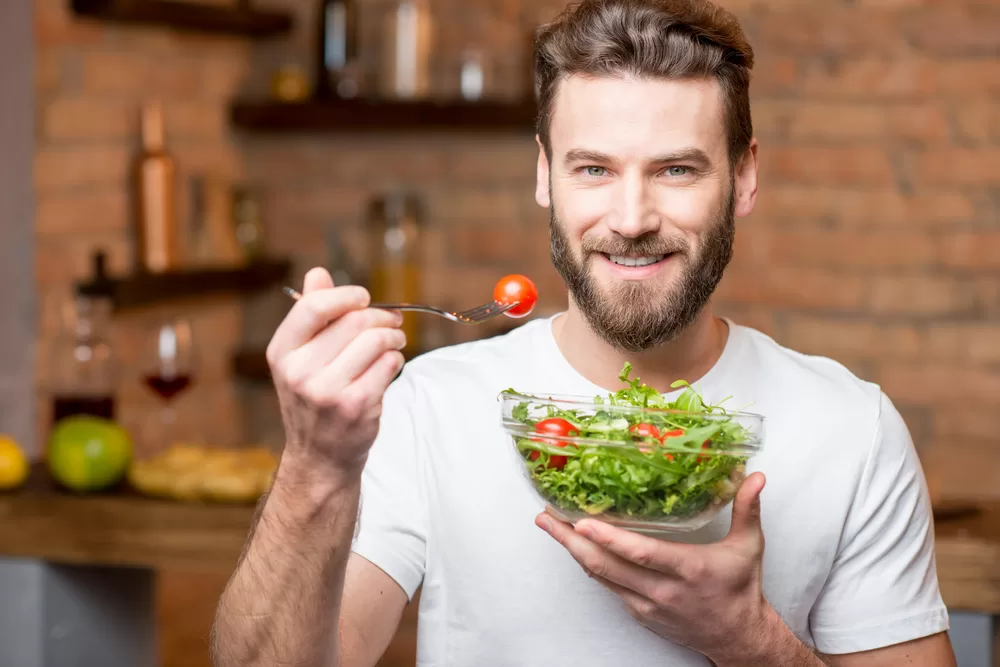 Young man with a beard eating a healthy green salad